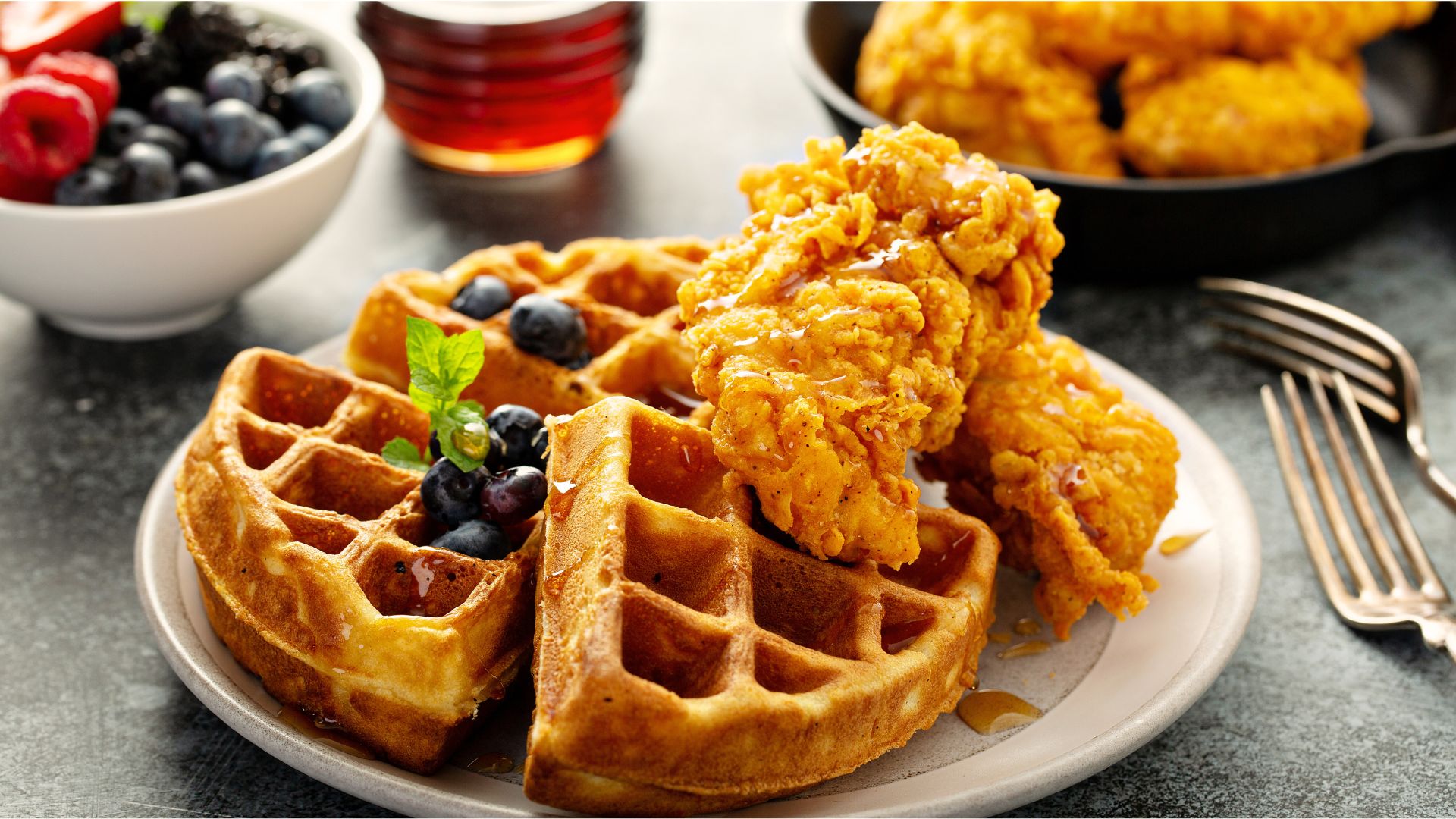 A plate of golden fried chicken served on fluffy waffles, drizzled with maple syrup, celebrating the sweet and savory flavors of National Chicken and Waffles Day.