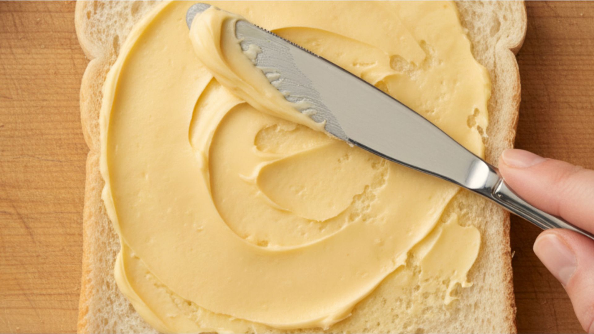 Close-up of butter being spread on warm toast, representing comfort, simplicity, and celebration for National Butter Day.