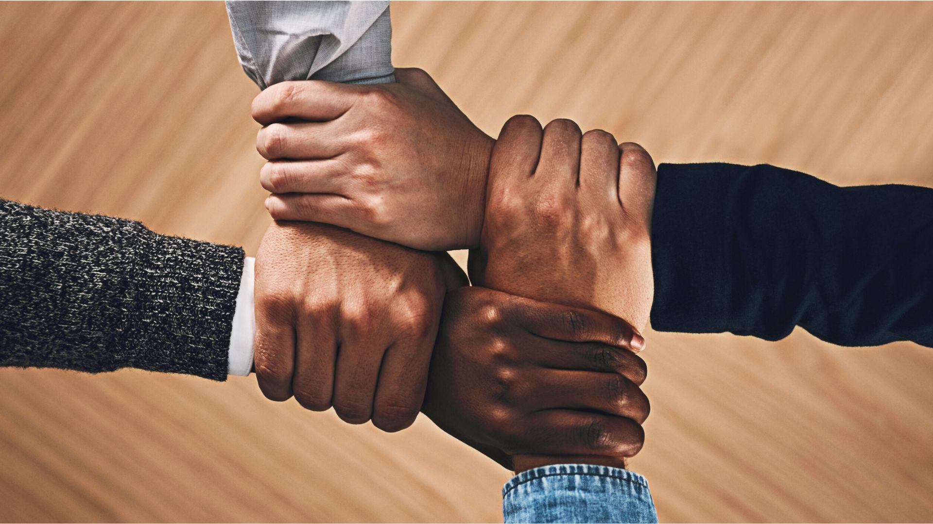 Four arms are shown holding on to the next as symbol of a strongly knit community and staff working together in a school environment, highlighting their essential role in daily operations.