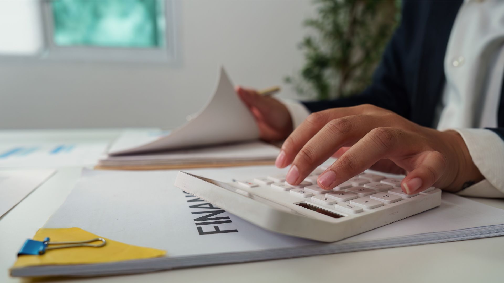 Person reviewing financial and legal documents at a desk while using a calculator, highlighting how legal planning supports overall financial wellness.