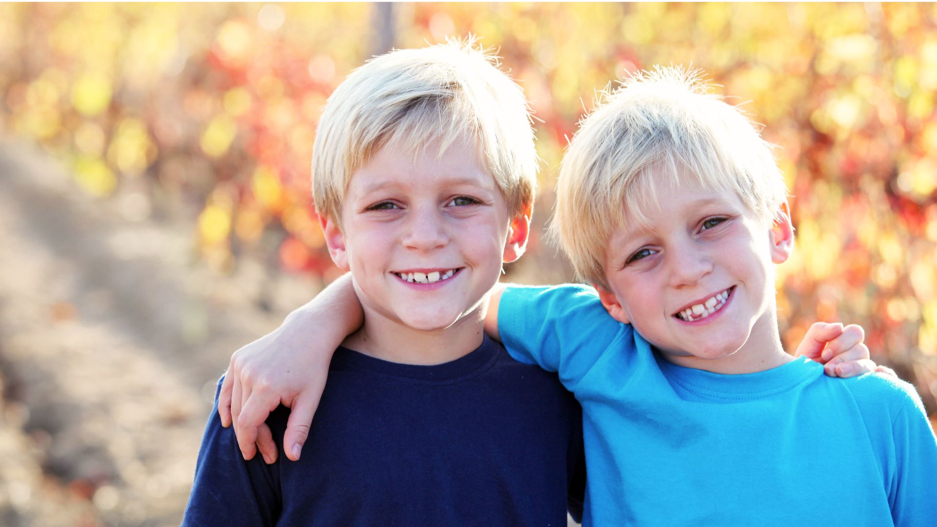 Twin siblings smiling together, highlighting the unique bond, shared experiences, and fascination of twinhood.