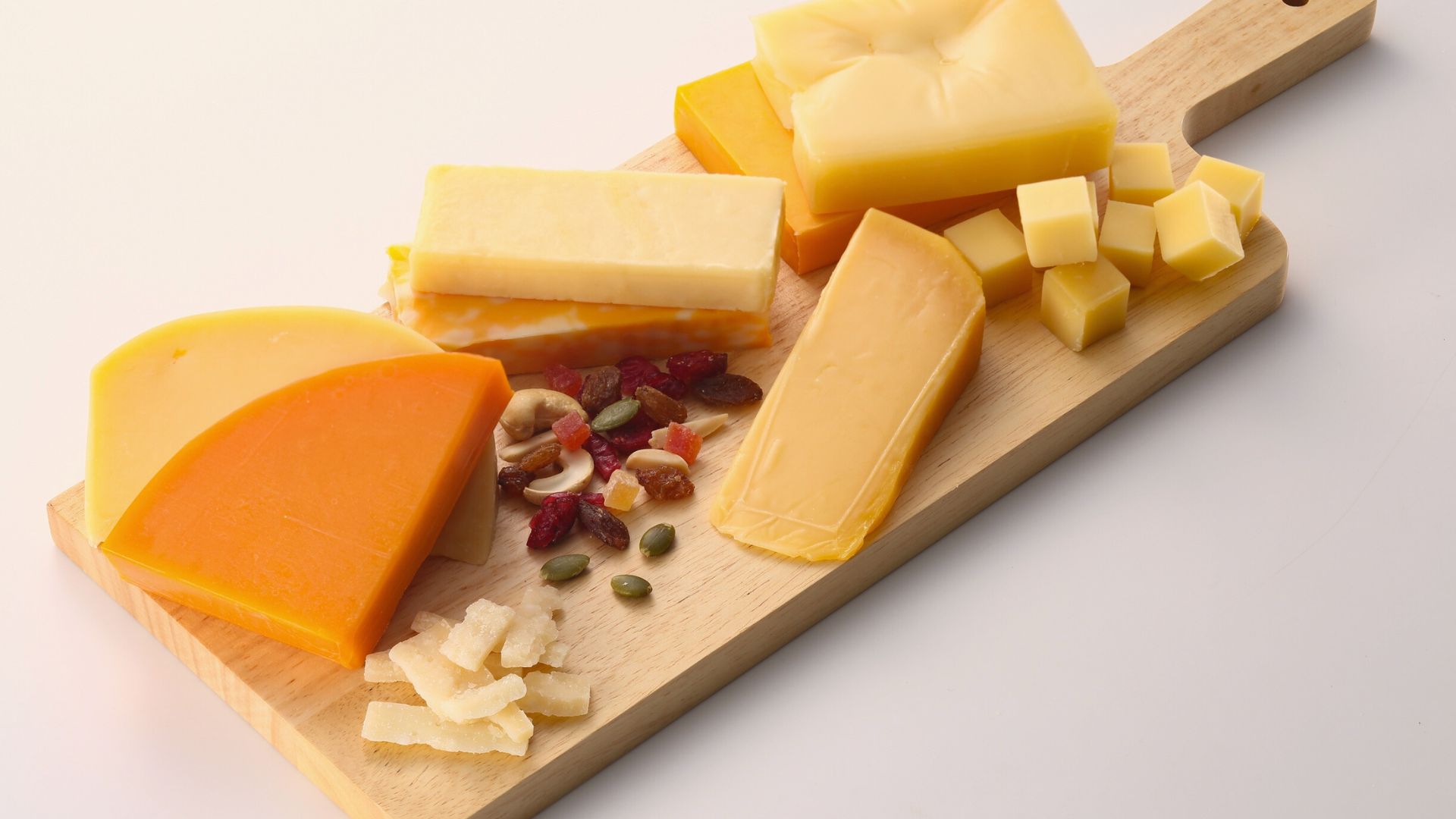 Assorted Wisconsin cheeses on a wooden board, symbolizing the state’s rich cheese culture and tradition.